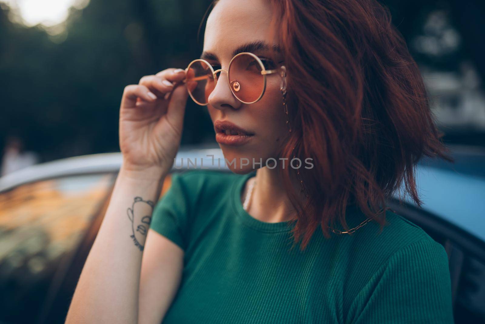 Young woman in glasses posing near car