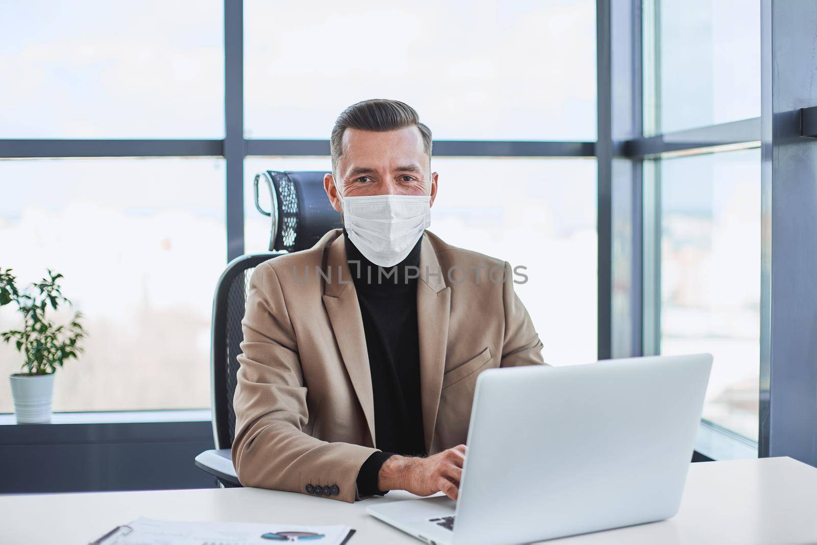 businessman in a protective mask sitting at his desk. close-up.