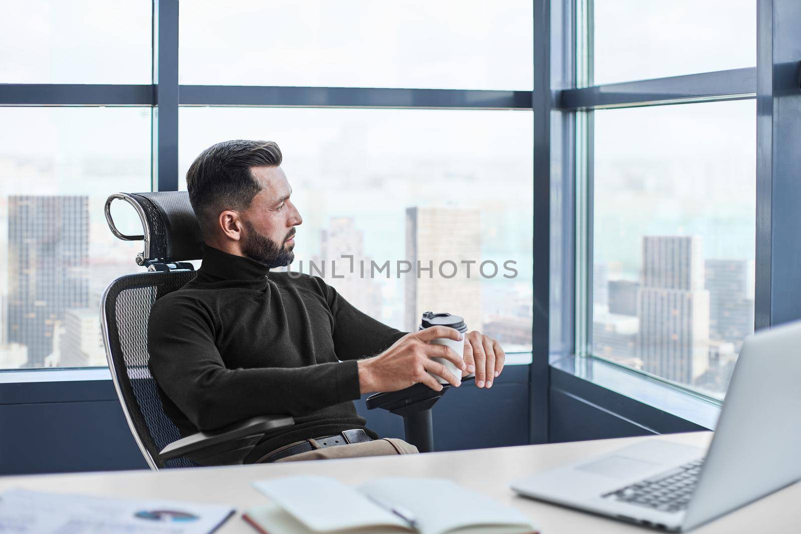 thoughtful businessman with takeaway coffee sitting at his desk. by SmartPhotoLab
