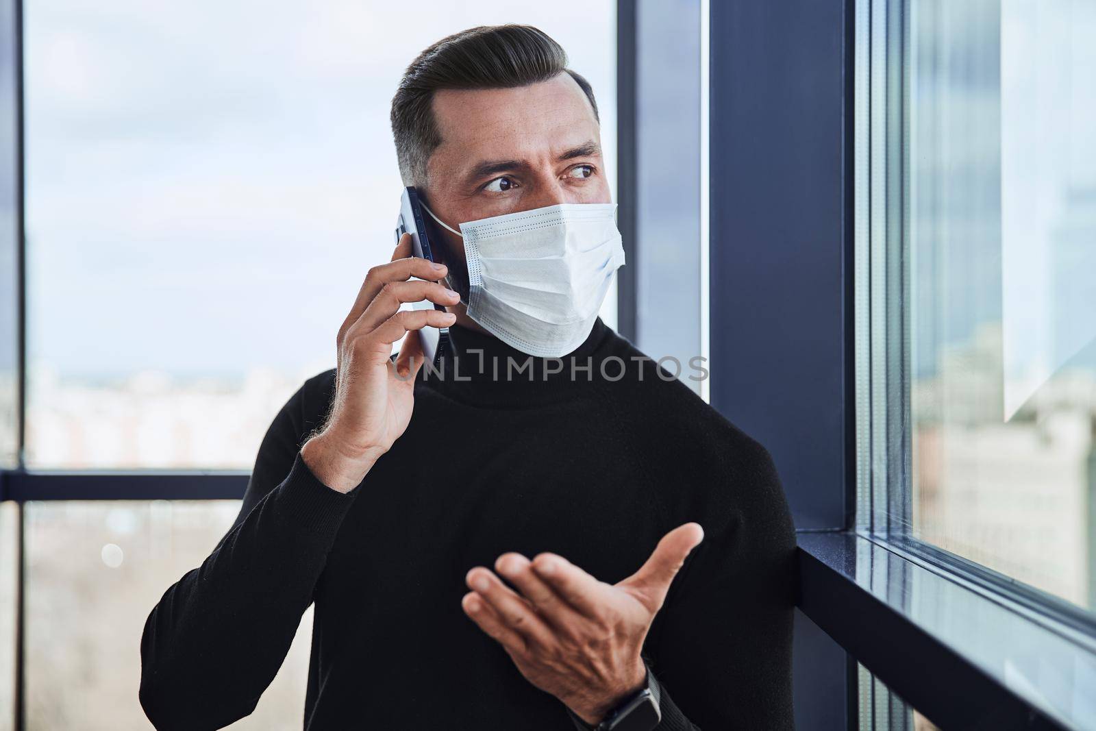 businessman in a protective mask communicating on a smartphone. by SmartPhotoLab