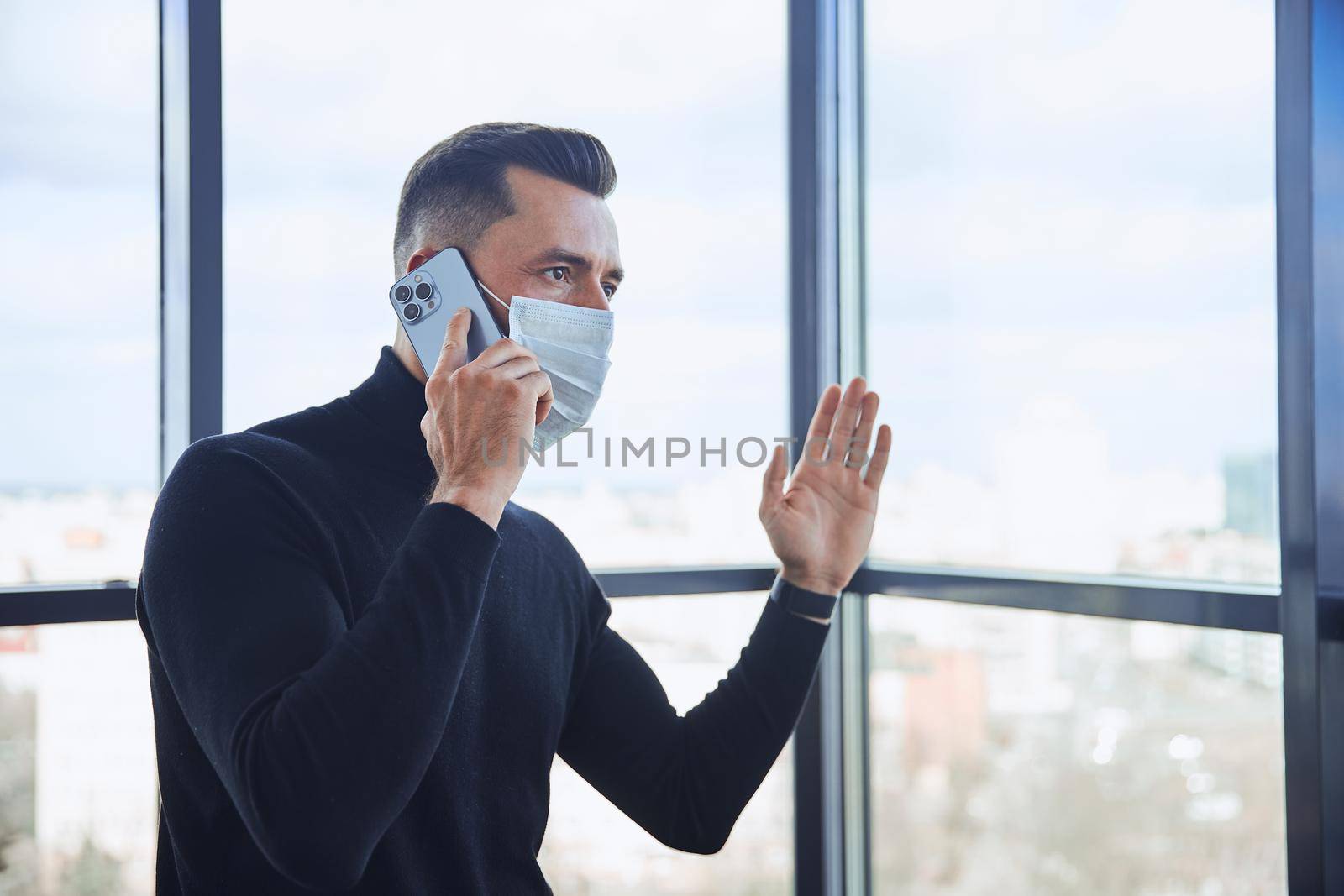 businessman in a protective mask communicating on a smartphone. by SmartPhotoLab