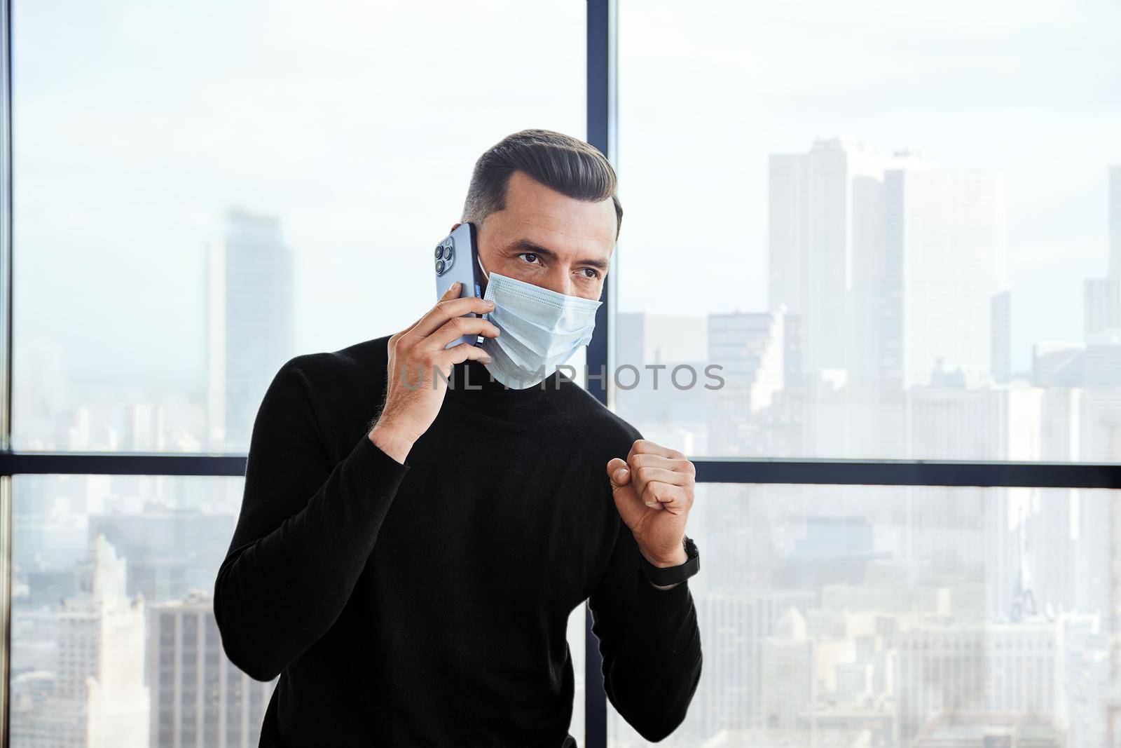 emotional businessman in a protective mask talking on a smartphone. by SmartPhotoLab