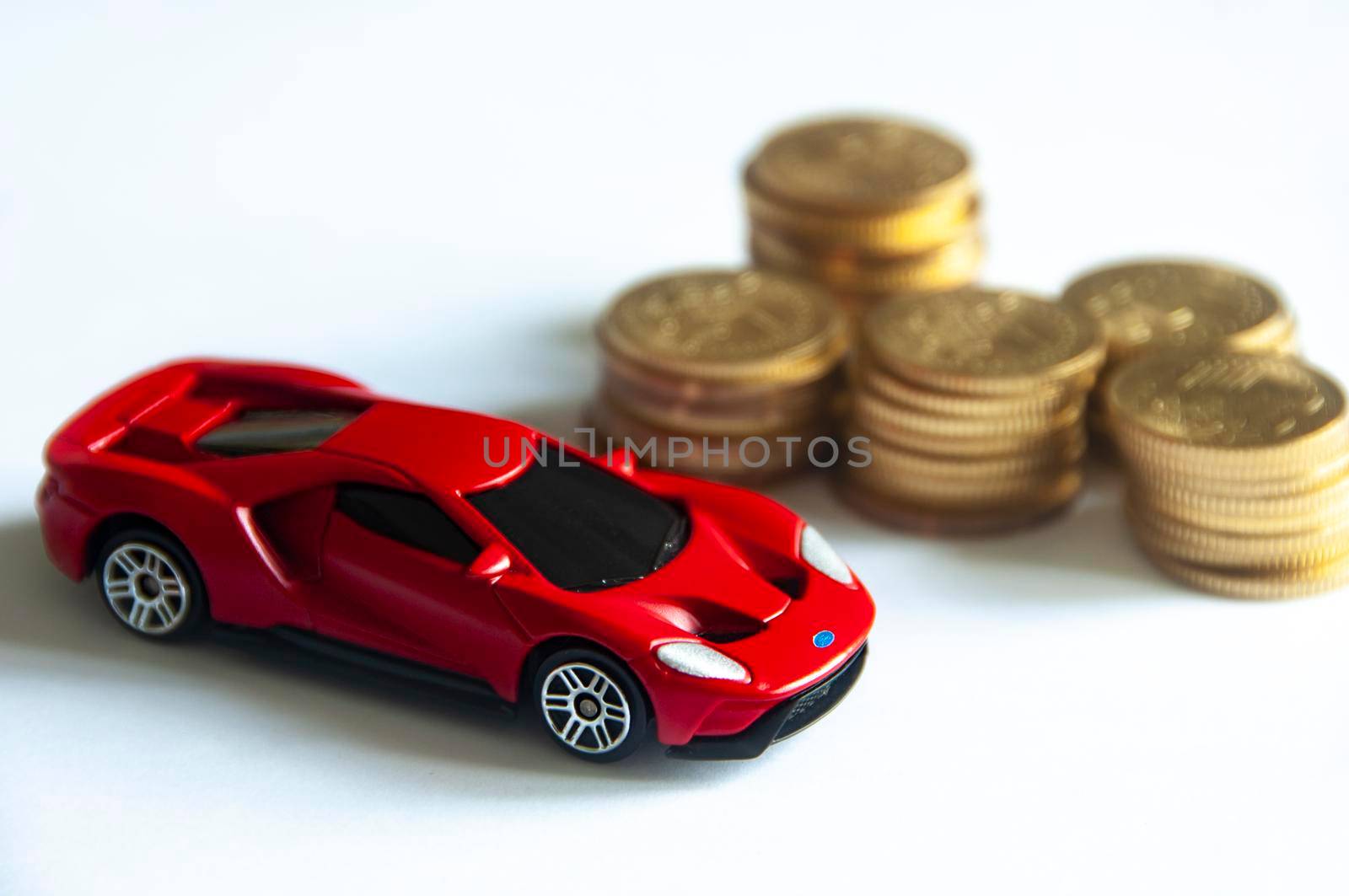 Kuala Lumpur, Malaysia - September 2022 : Selective focus of miniature toy car of Ford GT on white cover background with blurred gold coins. Copy space.