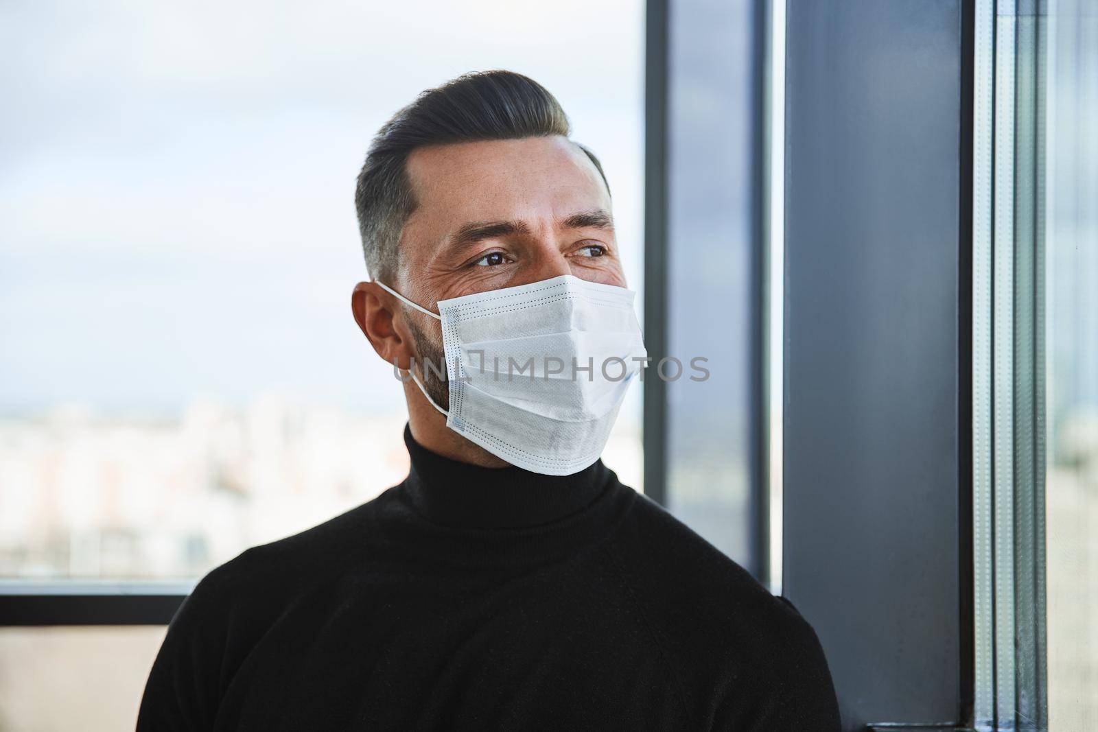 serious man in a protective mask standing near the window. close-up..