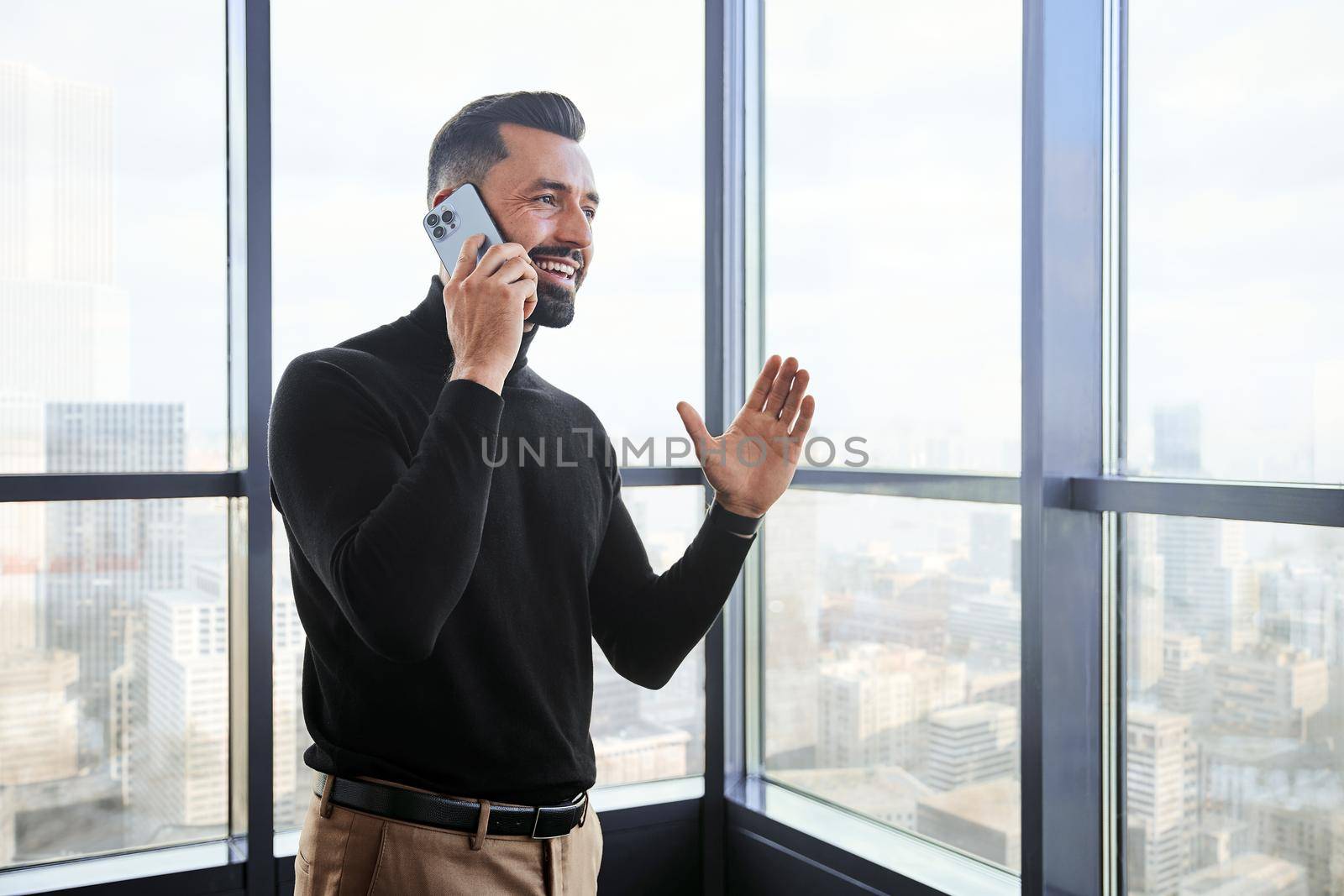 smiling business man talking on his smartphone near the window.