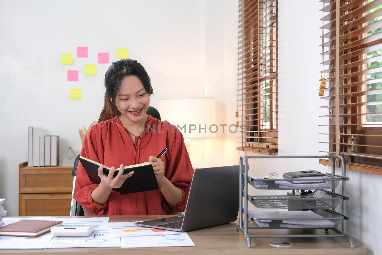 Young Asian businesswoman taking notes using a laptop at the modern office..