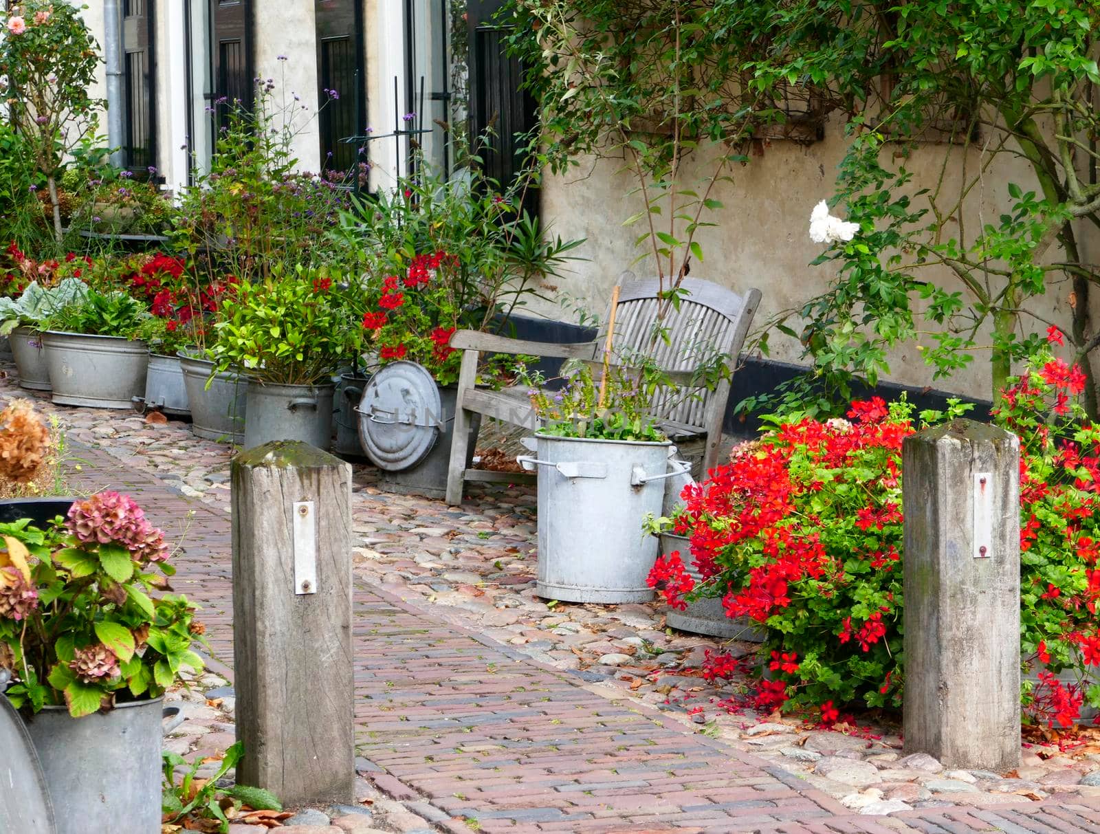 Small street near to the fortified wall with flowers in pots and buckets in the center of Elburg in the Netherlands.