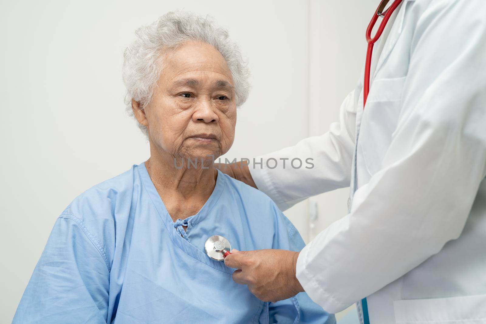 Doctor with stethoscope checking senior or elderly old lady woman patient while sitting on a bed in the nursing hospital ward, healthy strong medical concept. by pamai