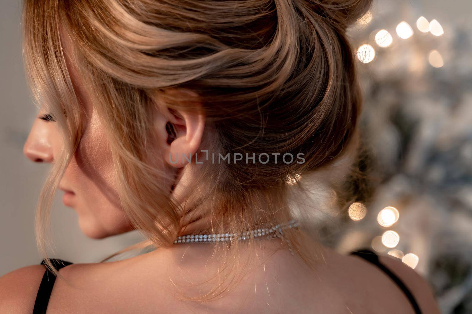 Portrait of a wealthy mature woman with evening makeup and hairstyle posing in a black dress against the backdrop of a Christmas room. Luxurious lifestyle. Cosmetology, plastic surgery, rejuvenation