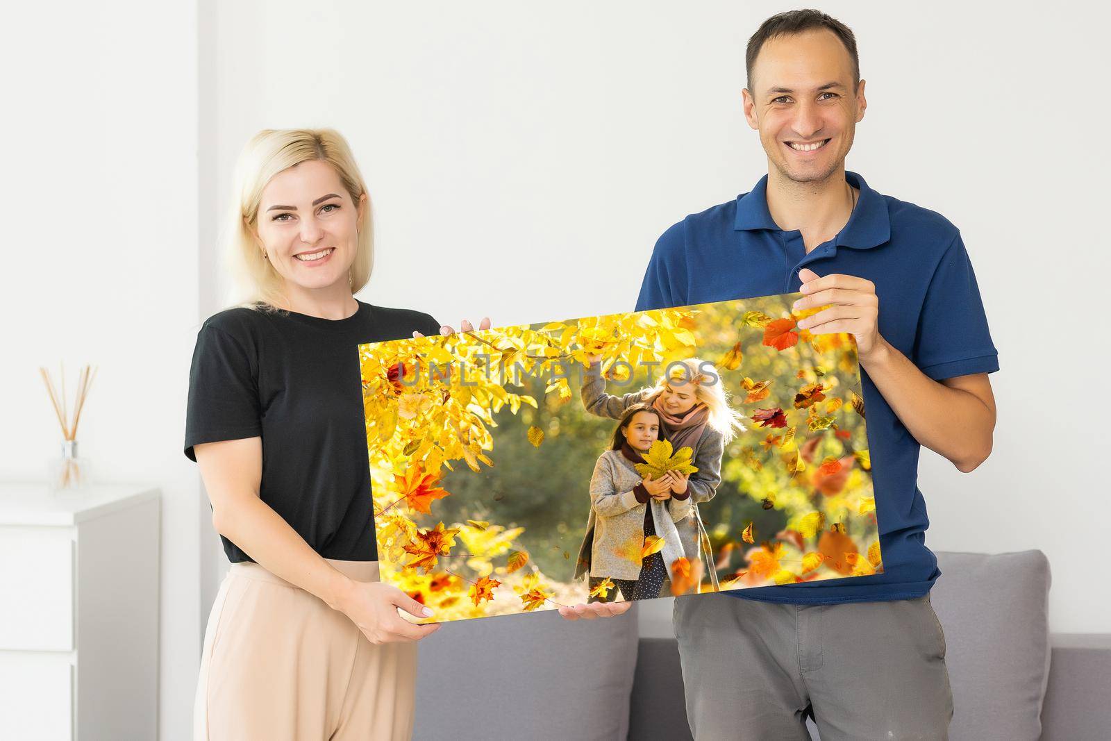 family holding photo canvas with autumn. couple with canvas