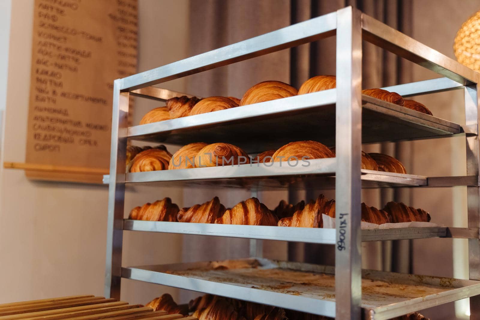 Production of delicious buns. Family bakery. Hot croissants on a metal tray. Fresh bakery. Rack with baked croissants.