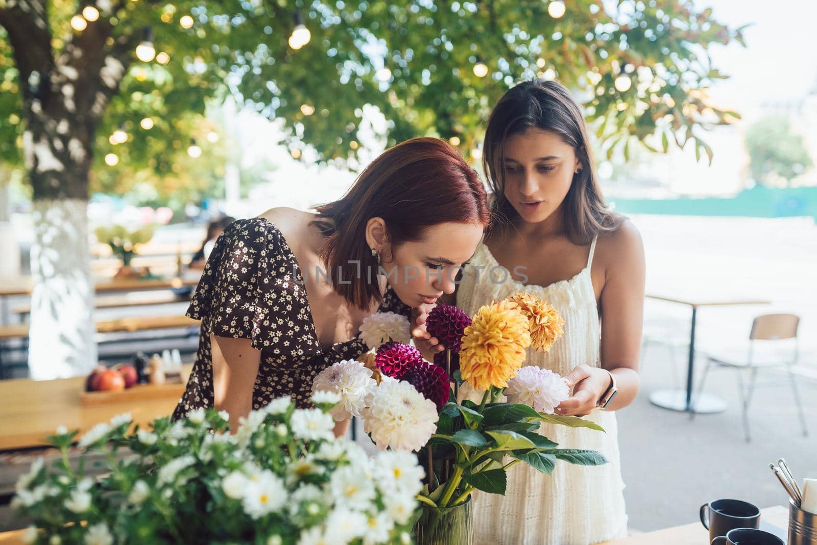 Two young women take orders and make up a beautiful festive bouquet. Floristry and making bouquets at the street caffe. Small business.