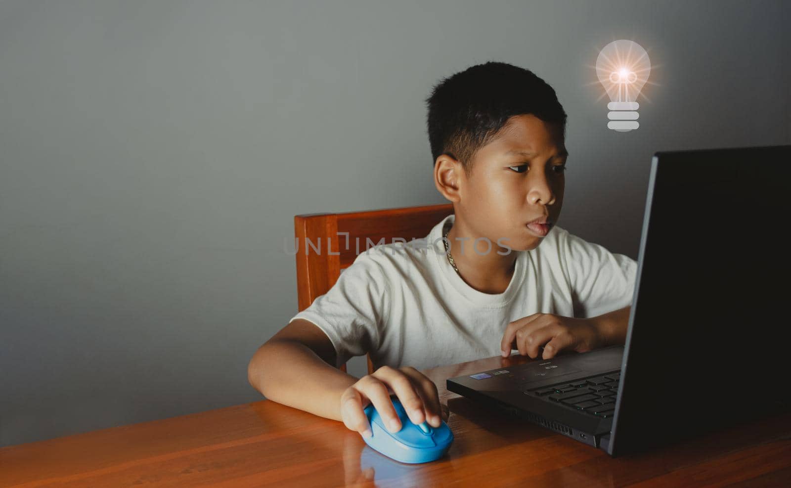 Close up The boy sits staring at the laptop and his hand is holding the mouse. educational concept, educational information search, copy space by Unimages2527