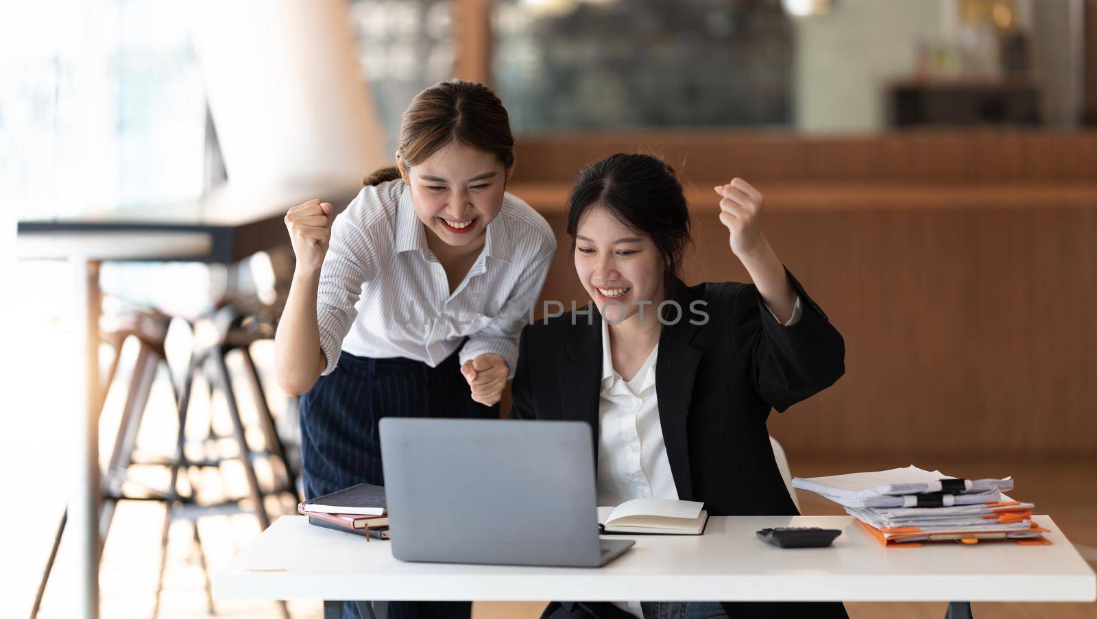 Two asian woman excited business team celebrate corporate victory together in office.