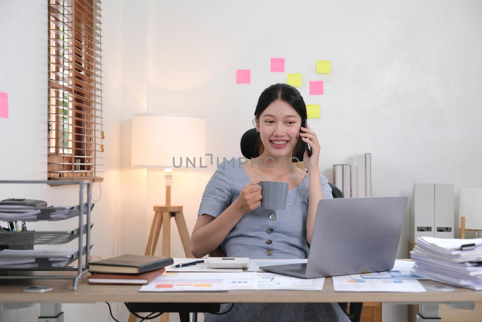 Business asian woman using smartphone for do math finance on wooden desk in office, tax, accounting, financial concept.