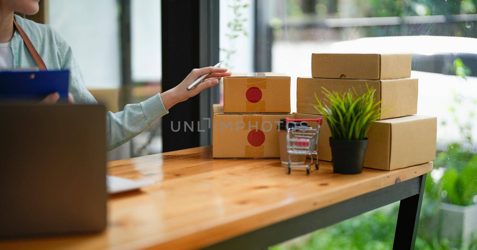 Startup small business SME, Entrepreneur owner using smartphone or tablet taking receive and checking online purchase shopping order to preparing pack product box. Selling online ideas concept.