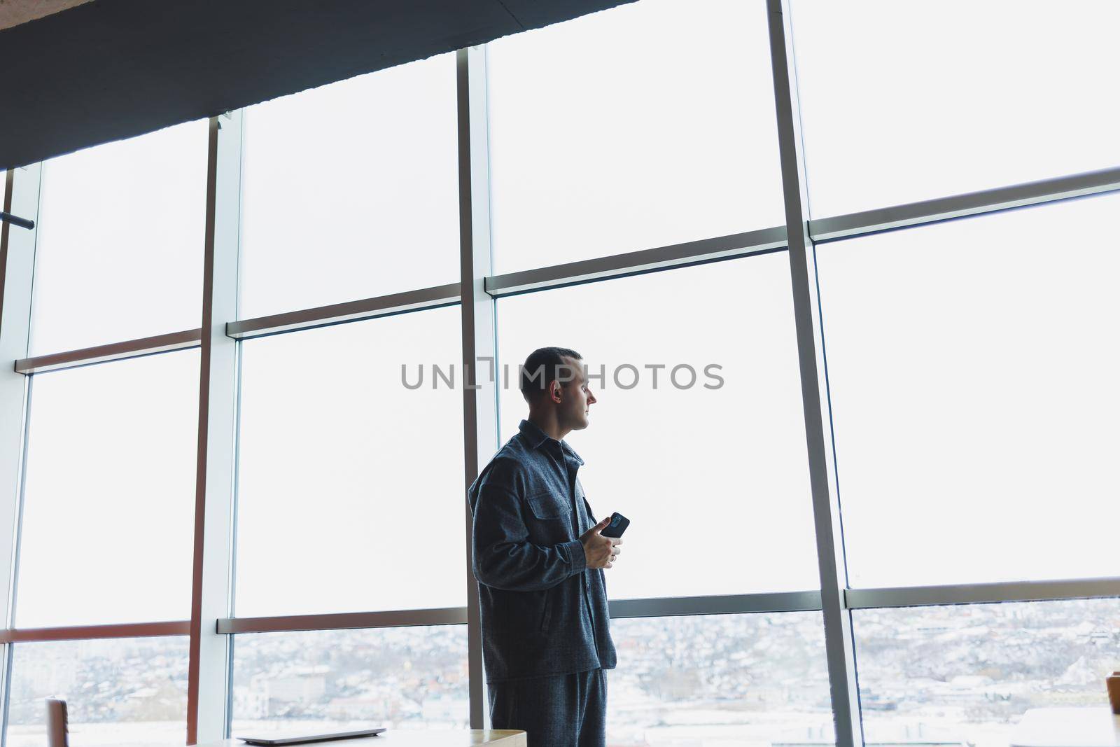 Young business man holding a phone. In an office or business center against the background of large windows of a skyscraper. Work and career, concept