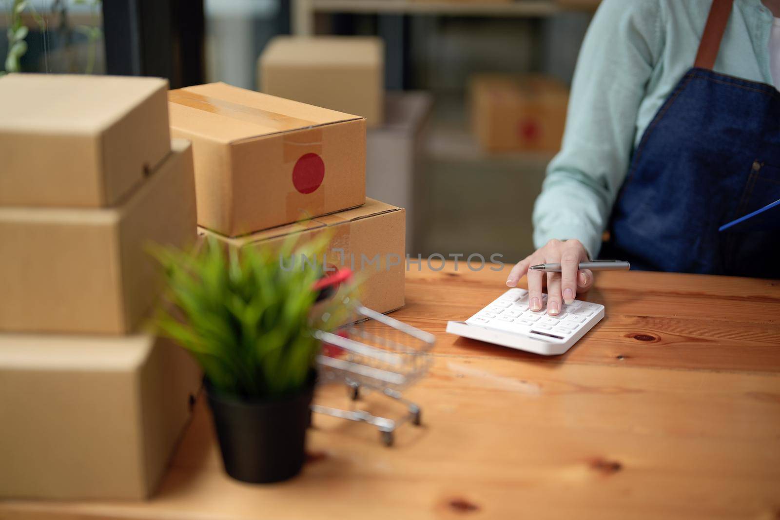 Close up woman start up small business owner calculation at workplace. small business entrepreneur SME or freelance asian woman working with box at home