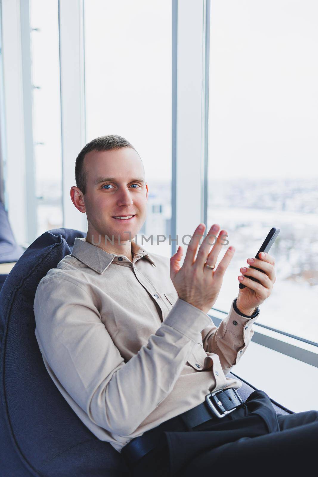 A businessman communicates with his clients by phone while sitting in a modern office workspace. Focused businessman sits alone in a modern workspace.