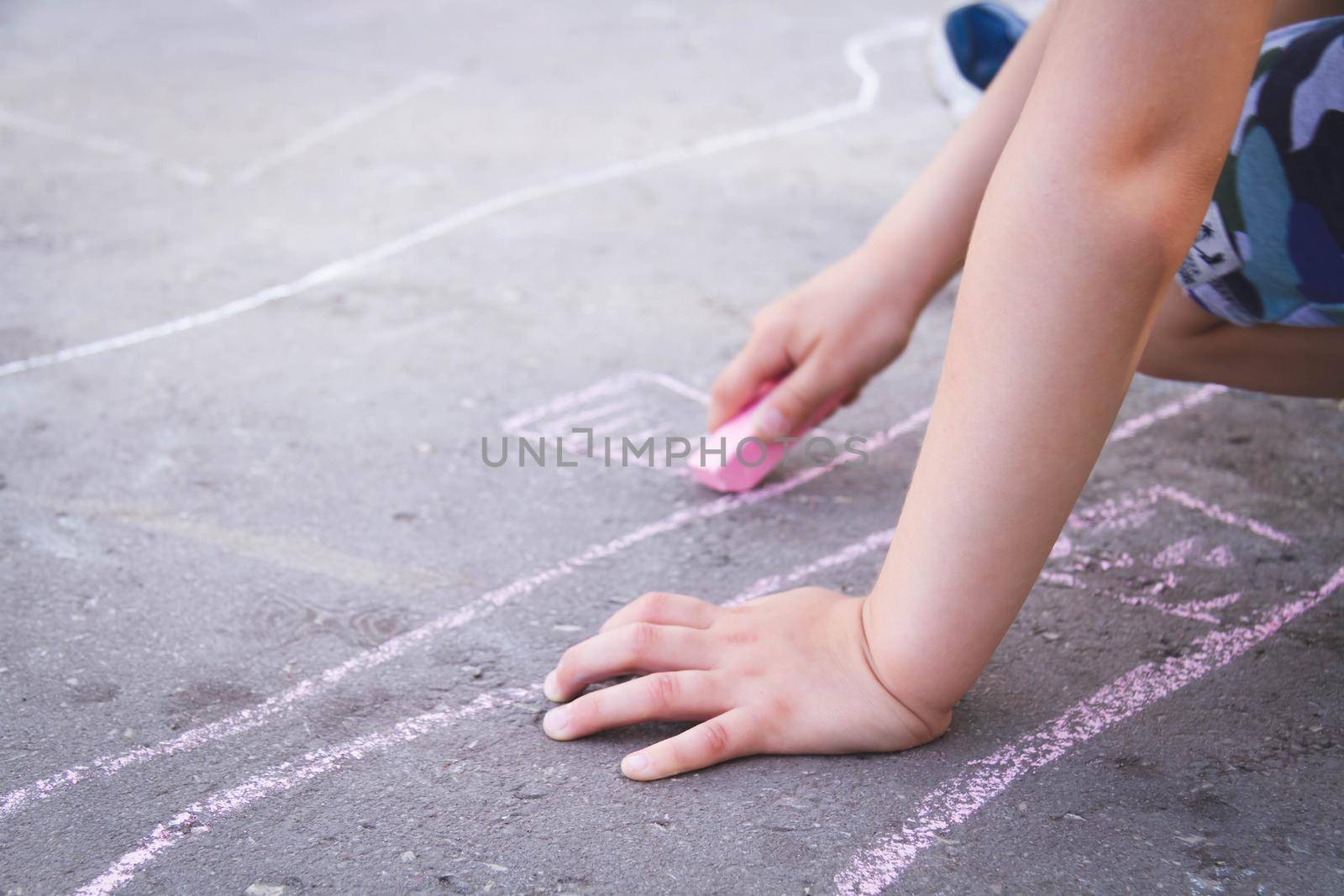Children draw with chalk on the road. Children's creativity on the street. by Verrone