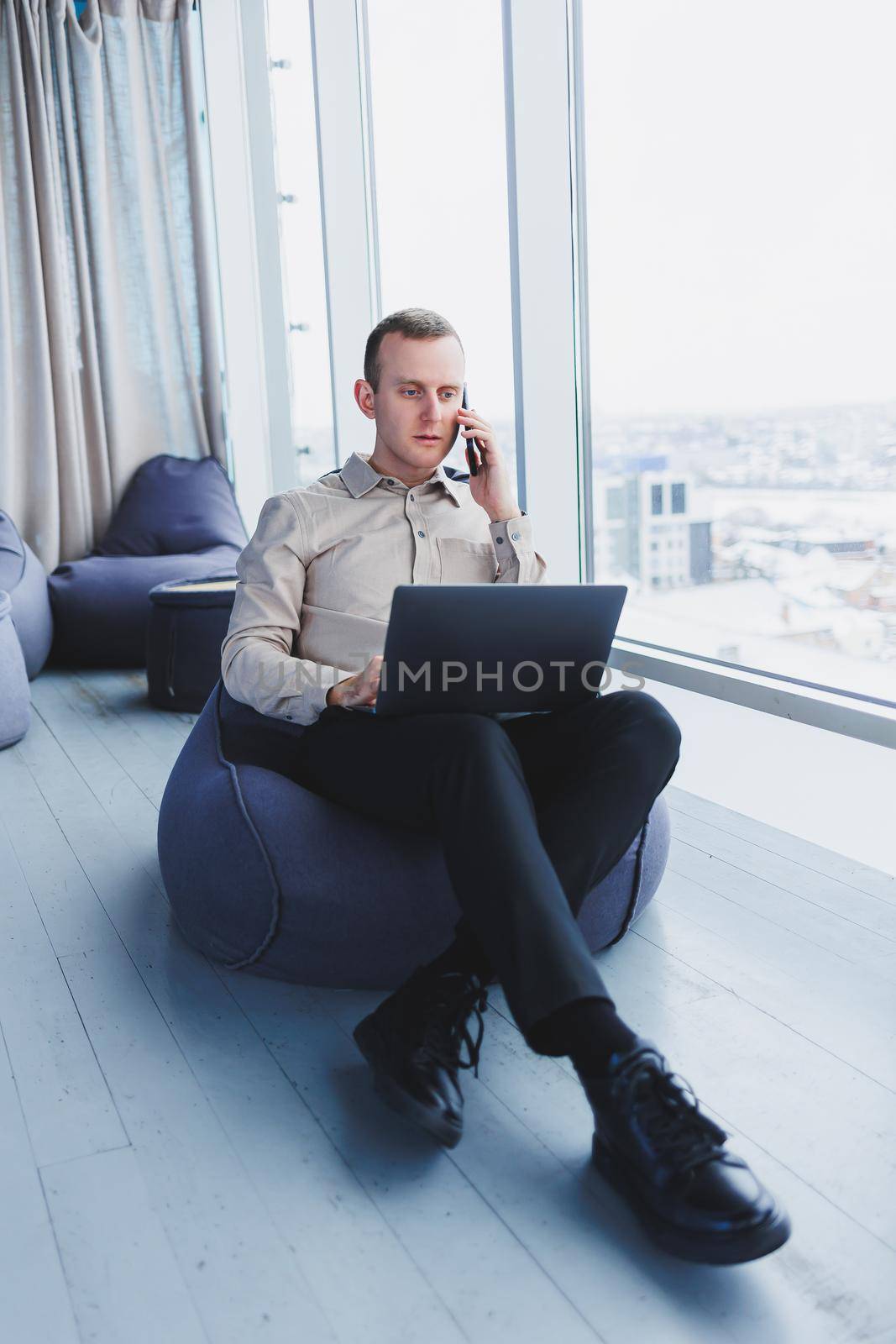 Concentrated young businessman looking at laptop screen, information online or working remotely online at home office, communicating remotely with client or study.