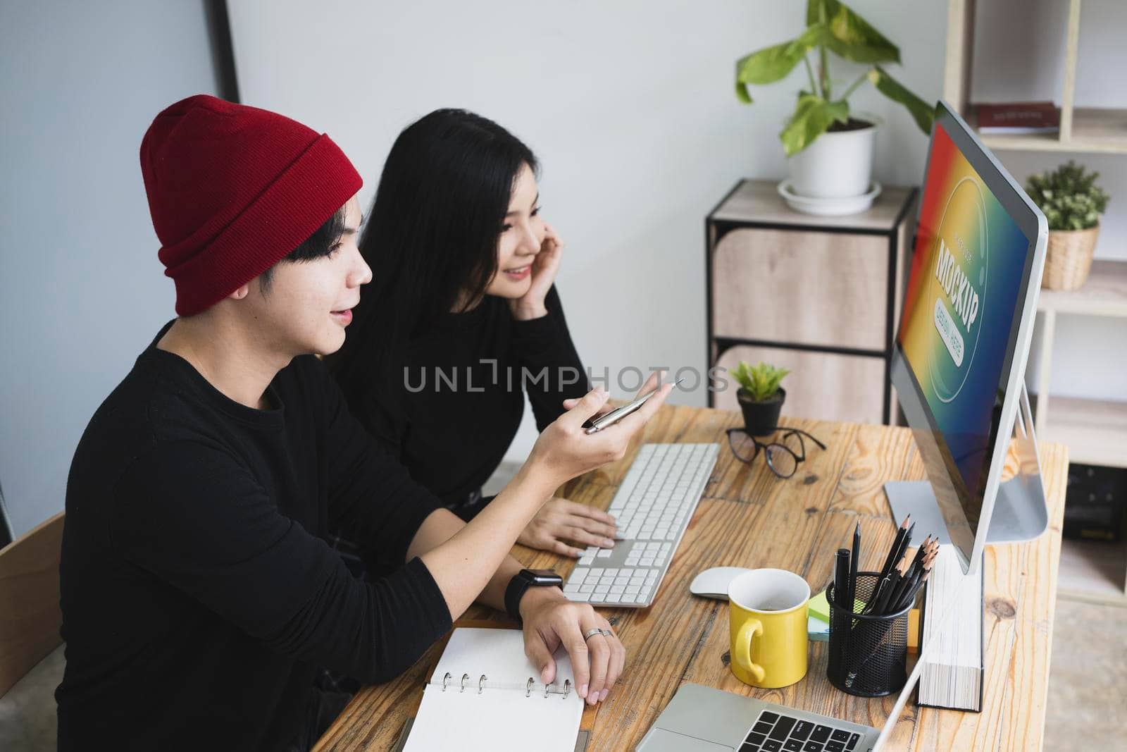 Two creative designer colleagues discussing project together in office.