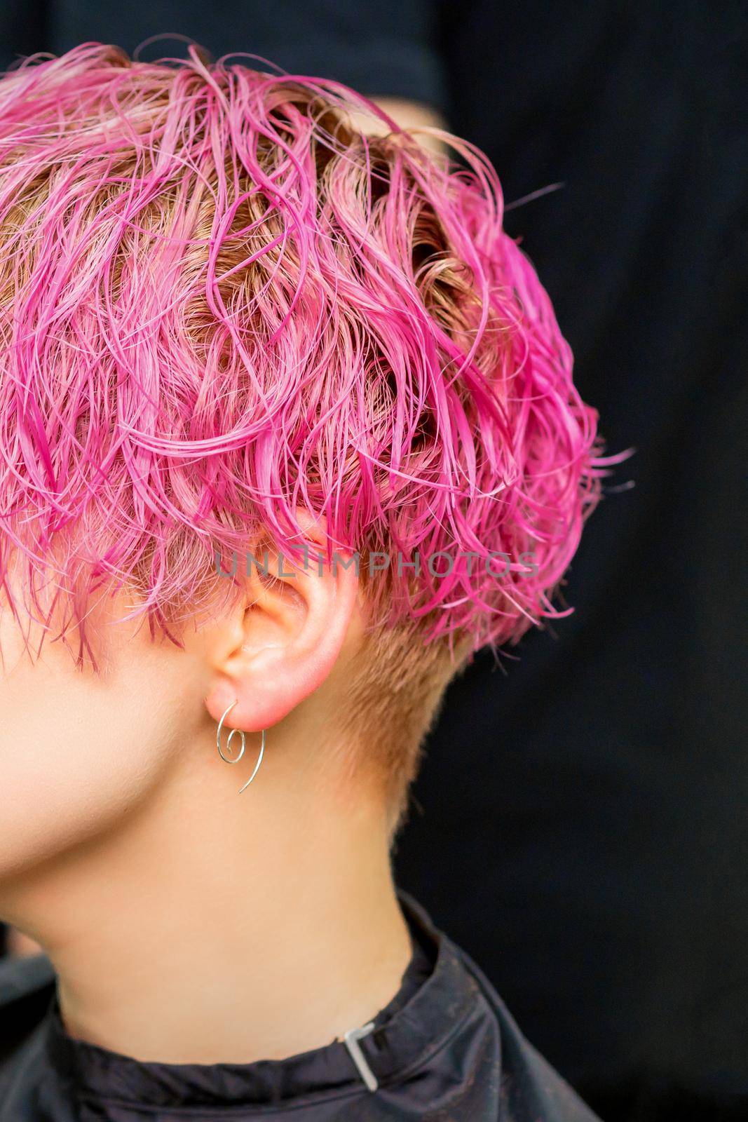 Beautiful young caucasian woman receiving new short pink hairstyle in hairdresser salon. by okskukuruza