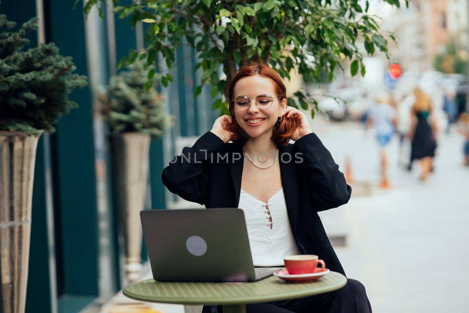 Happy young woman in a street cafe looks into the camera
