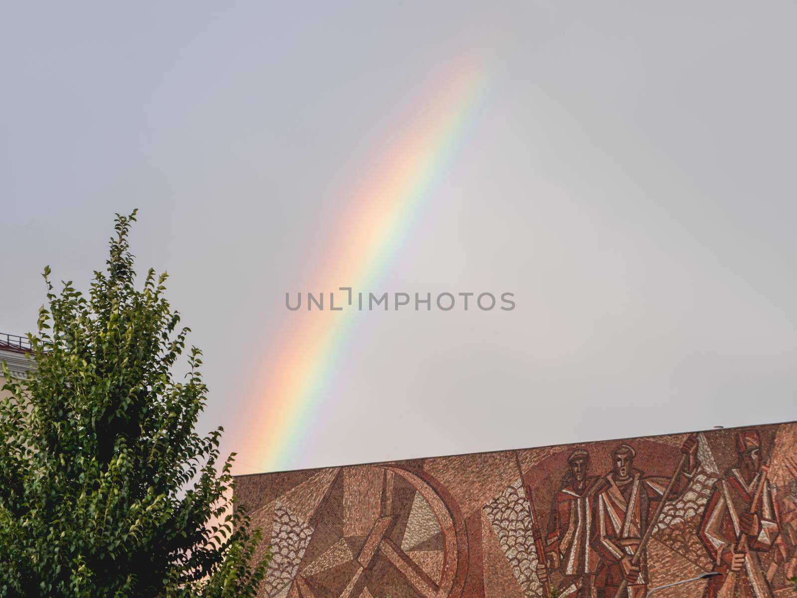 MOSCOW, RUSSIA - September 17, 2022.Bbright and colorful rainbow in the air. Cloudscape after rainfall over old cinema Oktyabr. by aksenovko