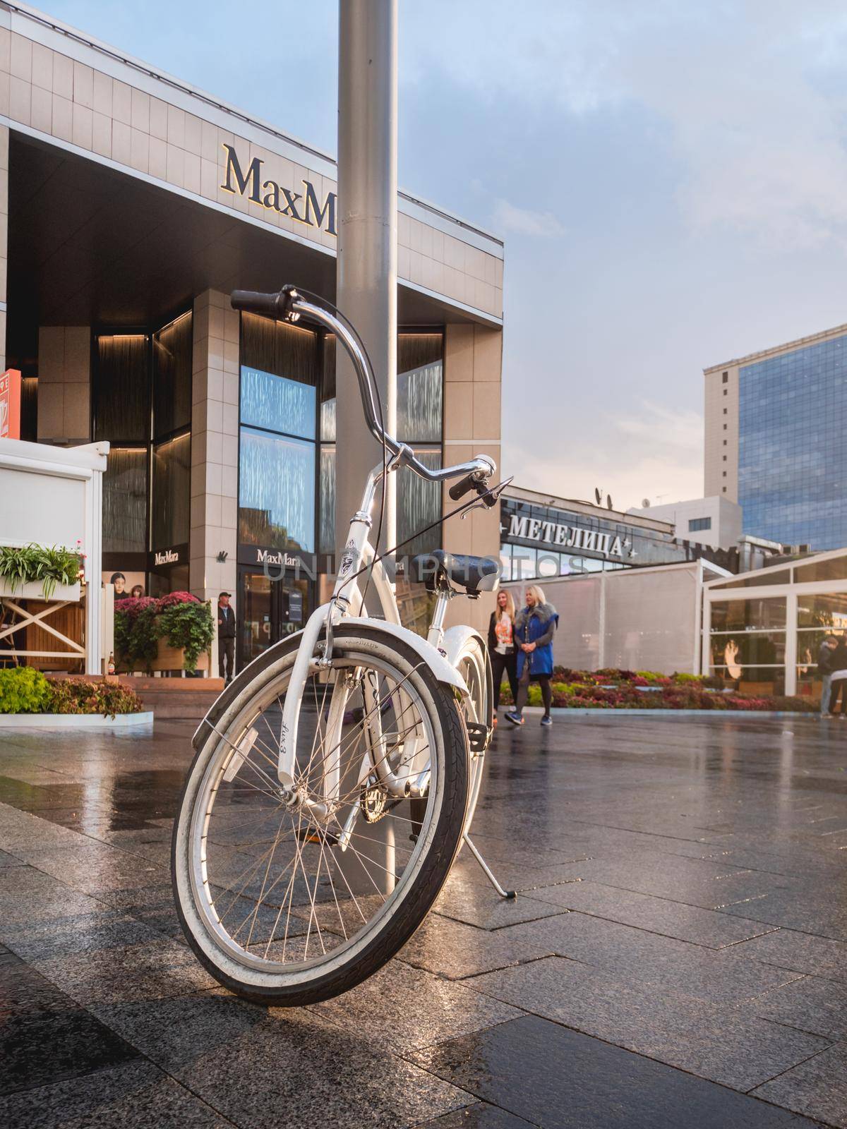 MOSCOW, RUSSIA - September 17, 2022. White bicycle parked on Novy Arbat. Wet pavement of famous street after rain. by aksenovko