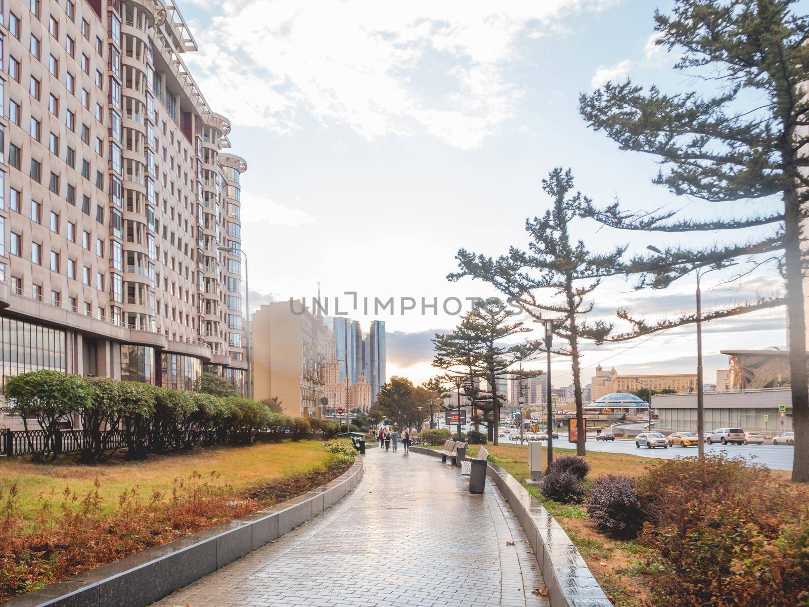 MOSCOW, RUSSIA -September 17, 2022. People are walking on alley along Novy Arbat street. Summer sunset in modern capital with lawns and skyscrapers.