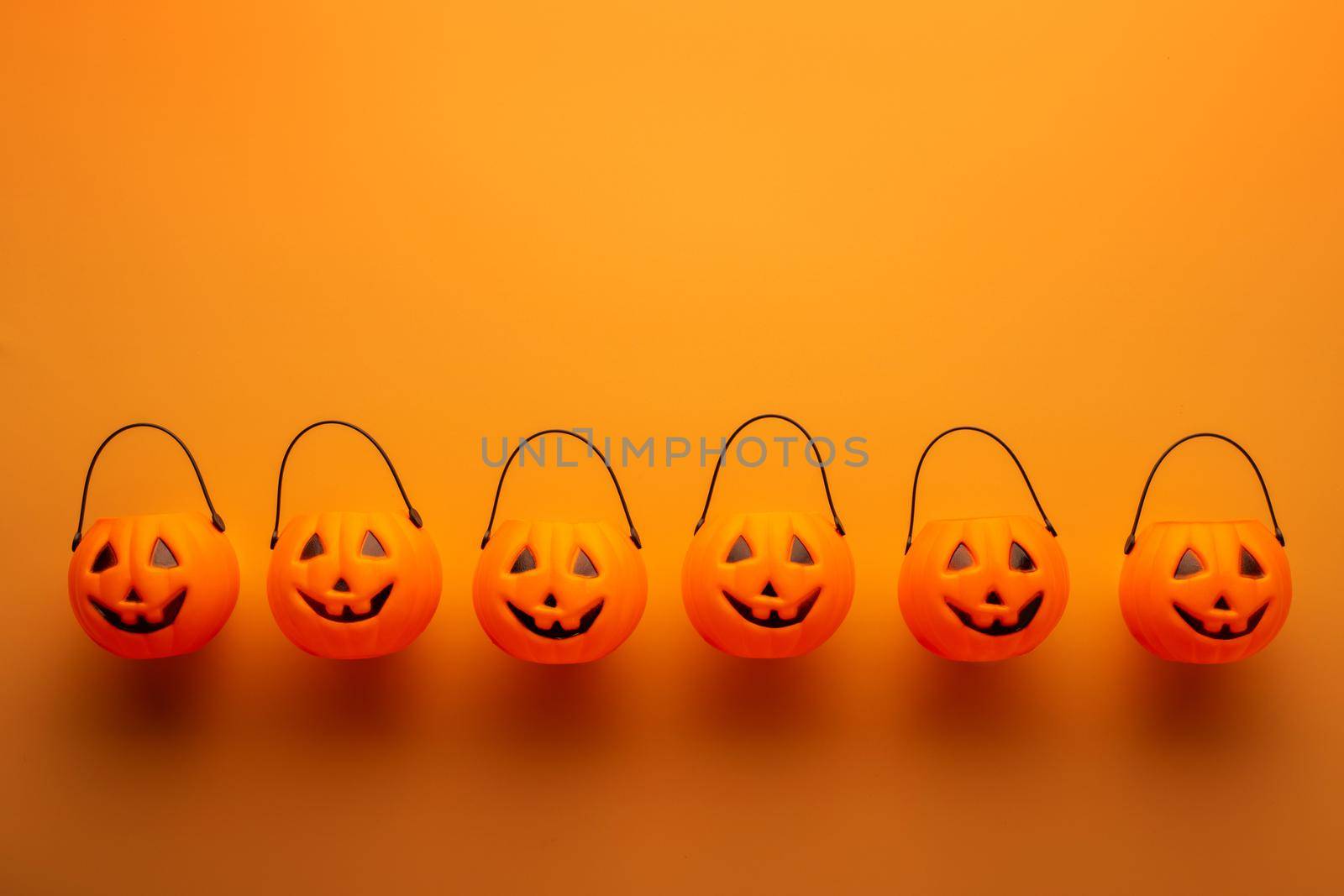 Halloween decorations with pumpkin baskets on orange background. Halloween concept. Flat lay, top view, copy space