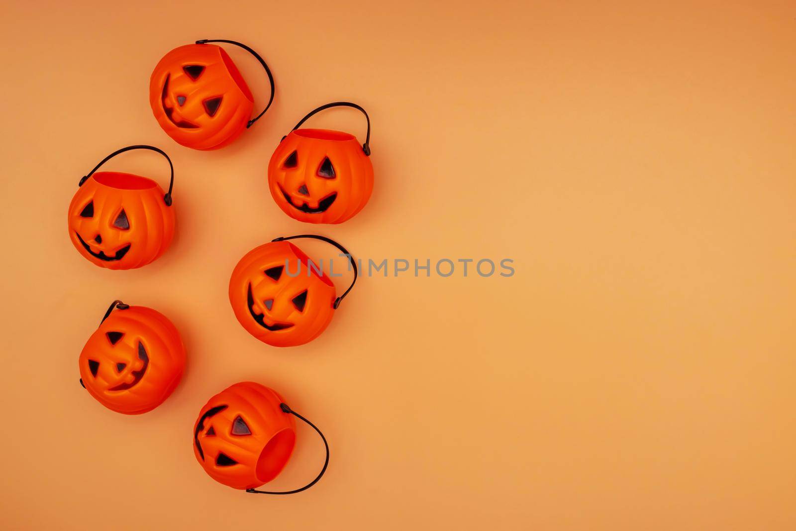 Halloween decorations with pumpkin baskets on orange background. Halloween concept. Flat lay, top view, copy space