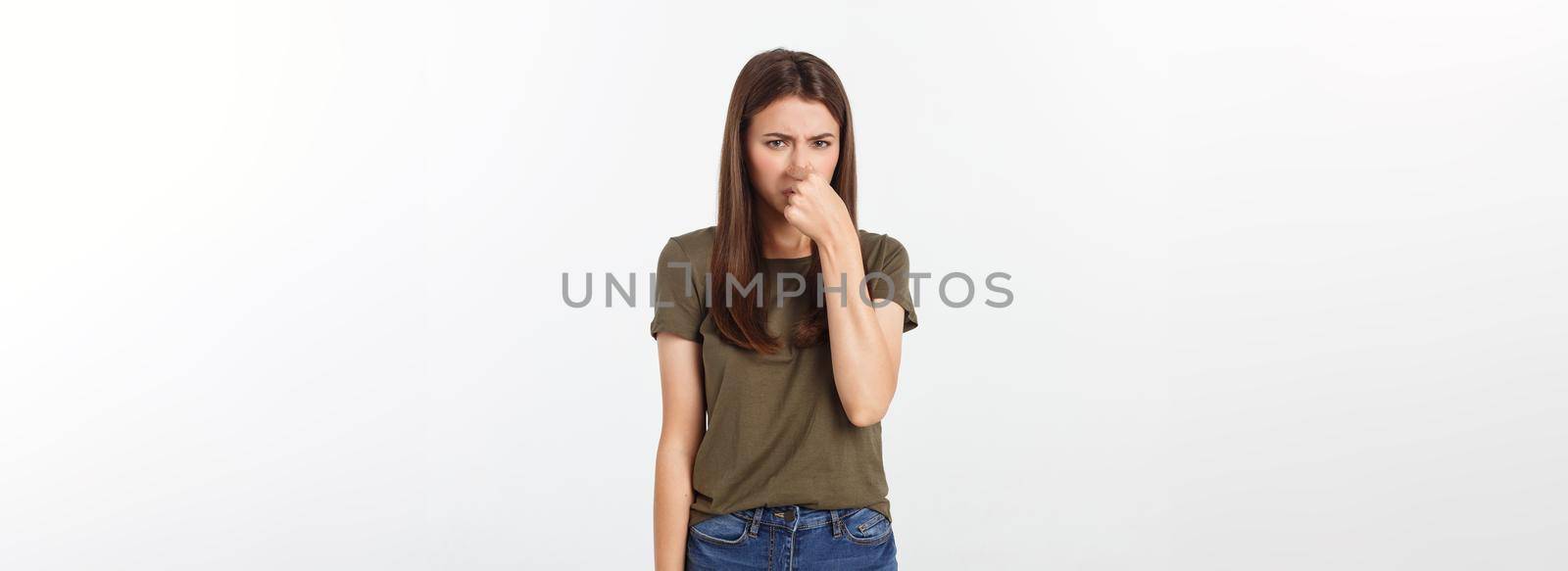Close-up portrait of a young attractive woman who covers her nose, something stinks, isolated on white background.