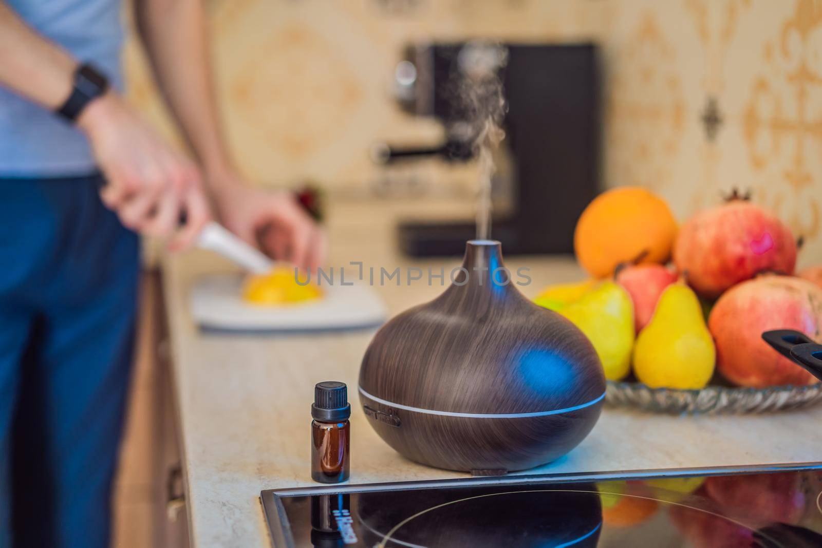 A man prepares food next to an aroma diffuser. cook cuts ripe red peppers in the kitchen. Cooking fresh, ripe, bell pepper salad for guests. Summer fresh vegetable salad.