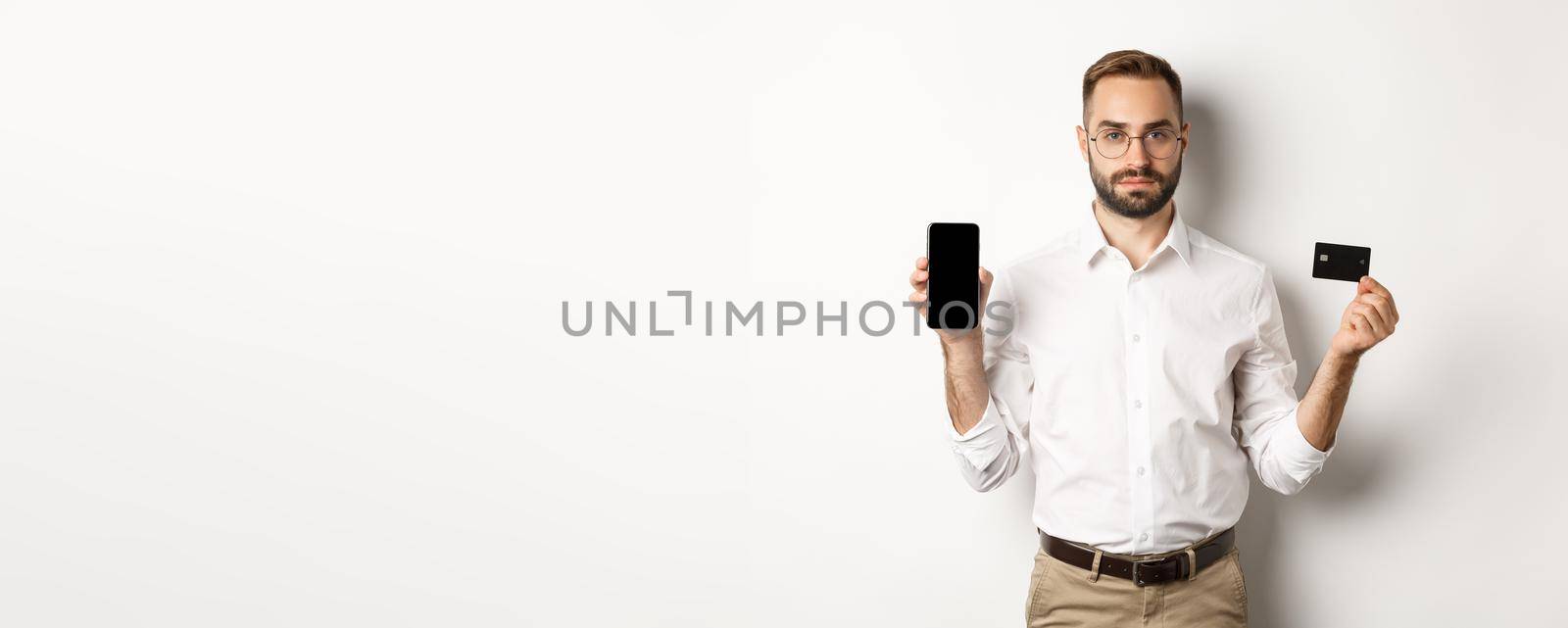 Serious business man showing mobile screen and credit card. Concept of online shopping.