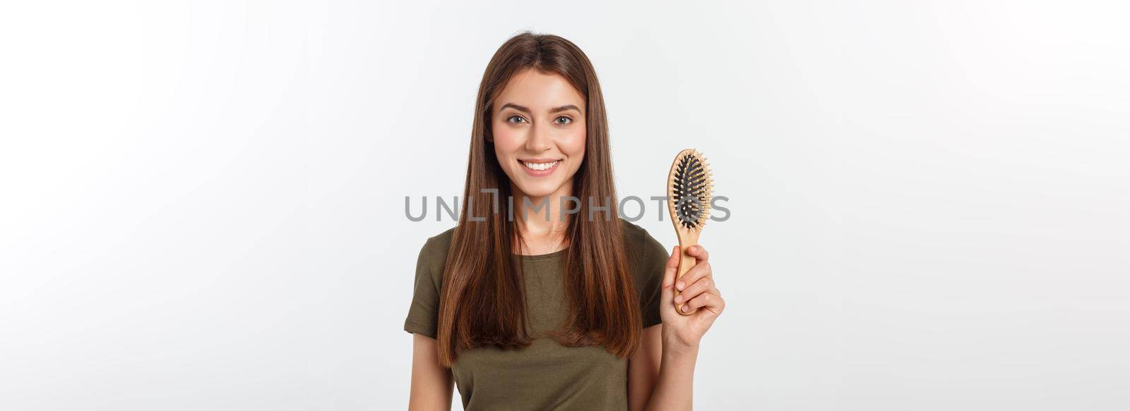 Happy young woman combing her long healthy hair on white background. by Benzoix