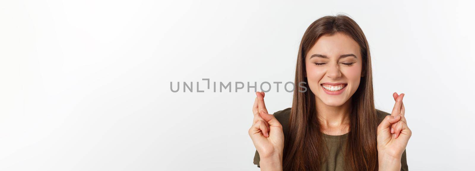 Closeup portrait hopeful beautiful woman crossing her fingers, open eyes, hoping, asking best isolated on gray wall background