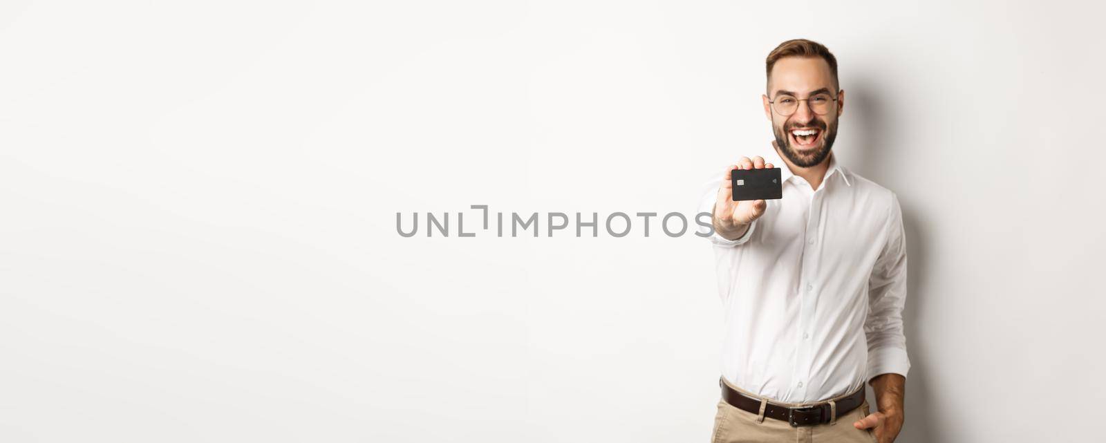 Excited caucasian man in glasses showing credit card, concept of shopping.