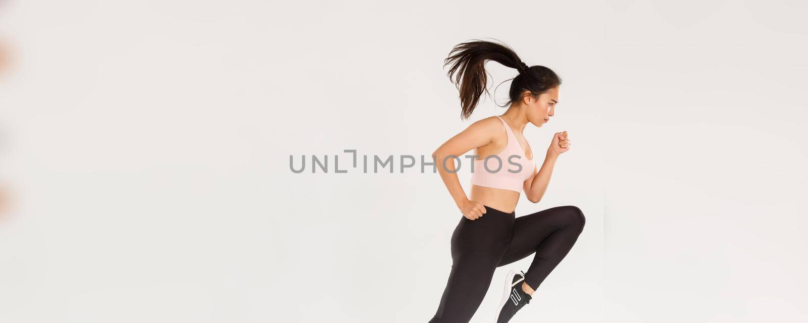 Sport, gym and healthy body concept. Full length of serious focused female runner, motion shot of girl running in air, fitness training of cute slim sportswoman, athlete workout in active wear.