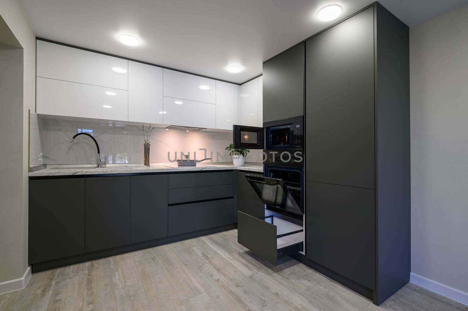 Showcase interior of modern simple trendy dark grey and white kitchen, drawers retracted