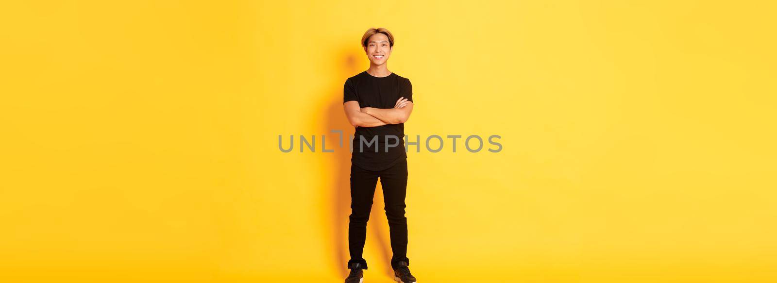 Full length of smiling confident asian blong guy, cross arms chest over yellow background by Benzoix