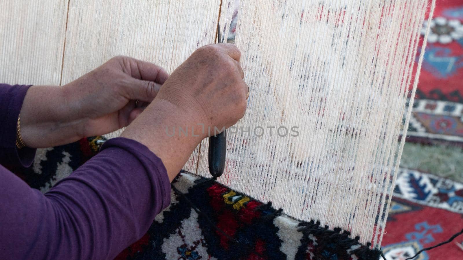 Women's hands knit carpet on a loom, textile industry by voktybre