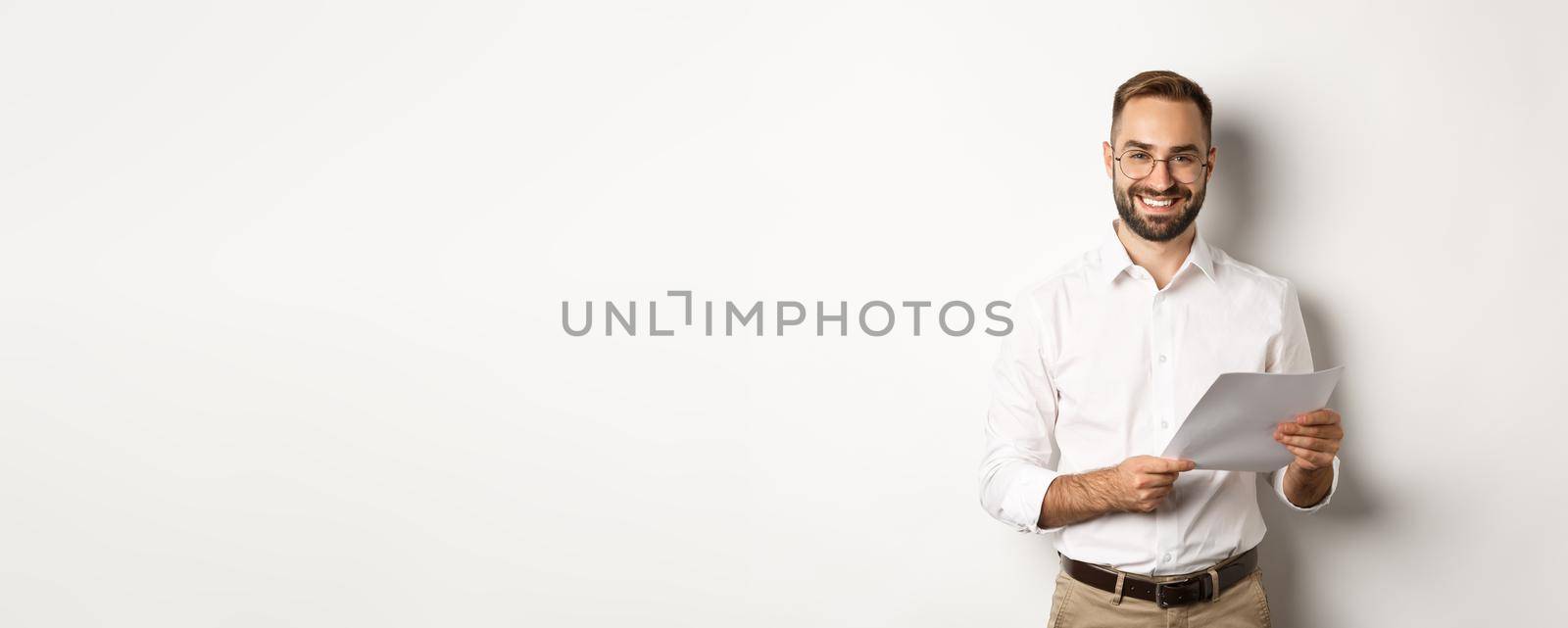 Employer looking satisfied with work, reading documents and smiling pleased, standing over white background by Benzoix