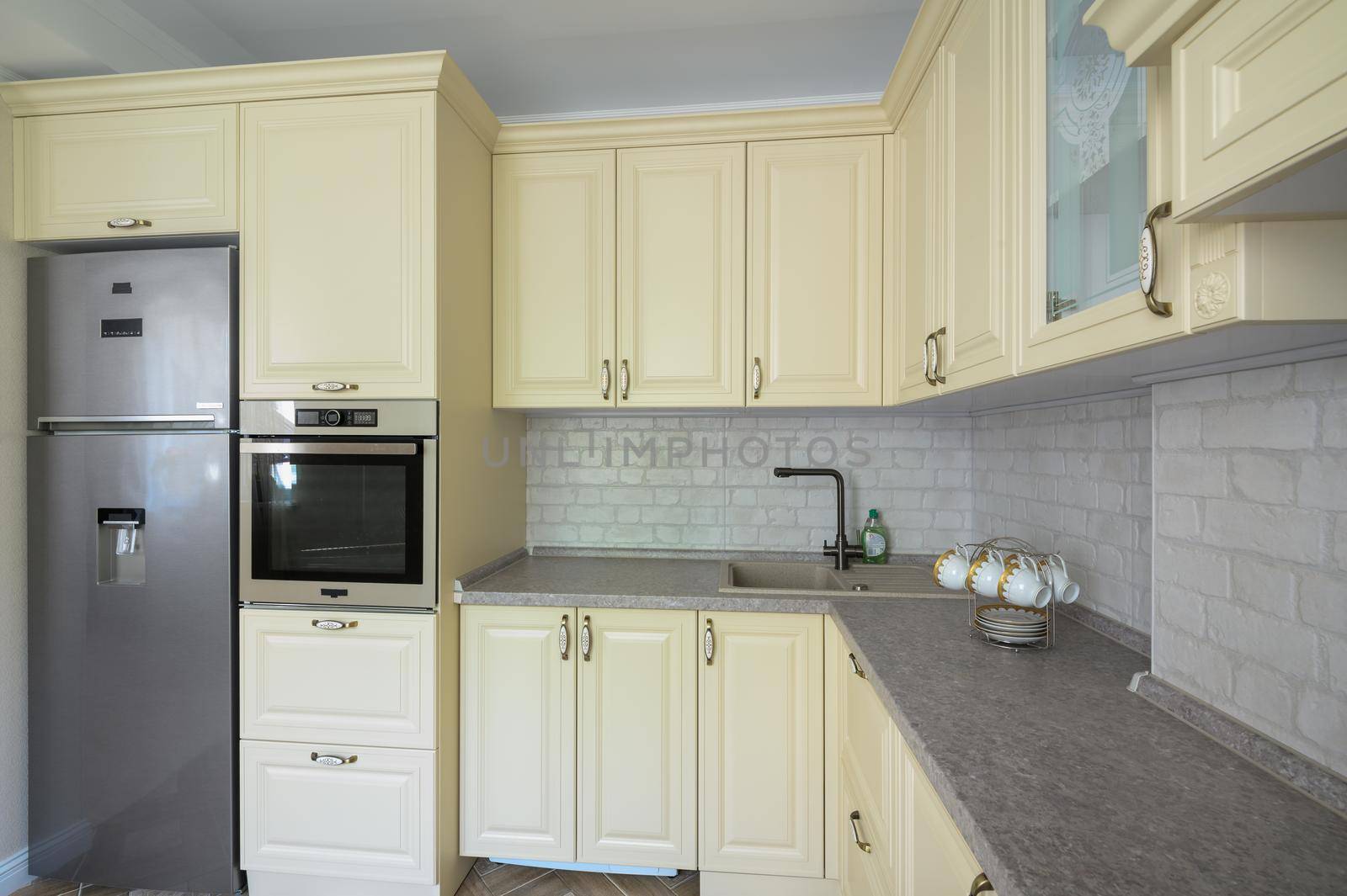 Real showcase interior of modern trendy cream colored kitchen