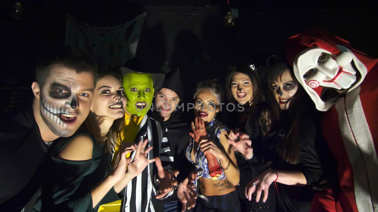 Halloween party, night, twilight, in the rays of light, young people frighten the spectators, everyone is dressed in scary costumes for Halloween. High quality photo
