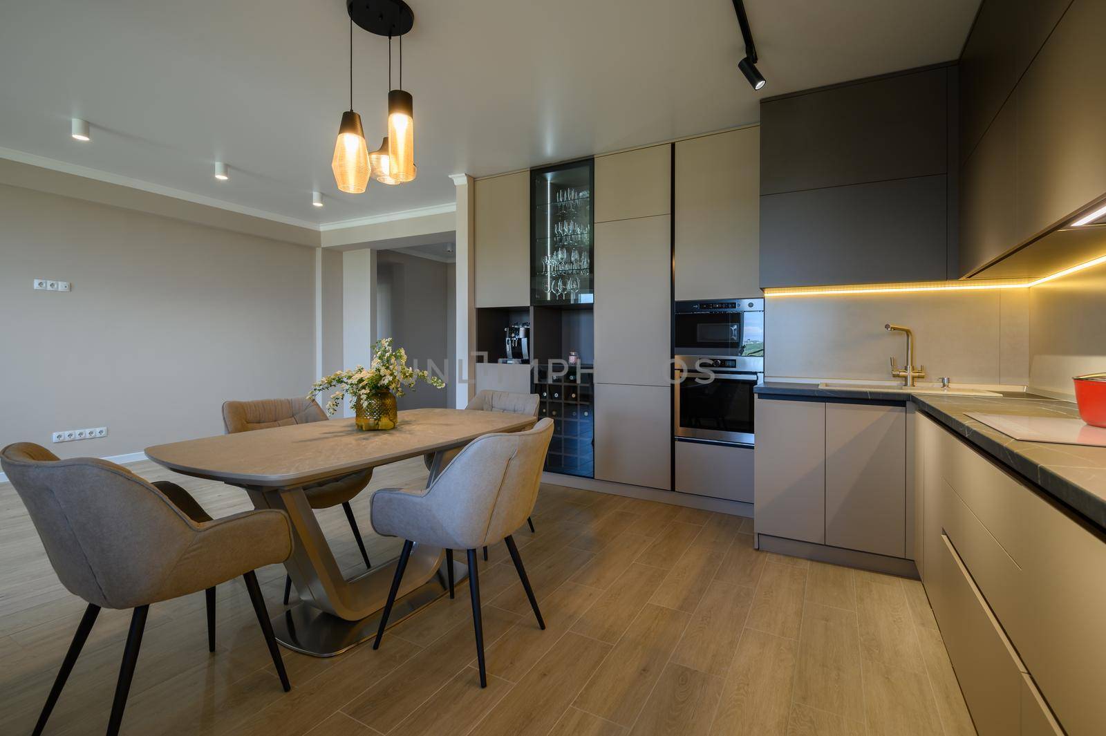 Large modern grey luxurious kitchen with dining table in studio apartment interior