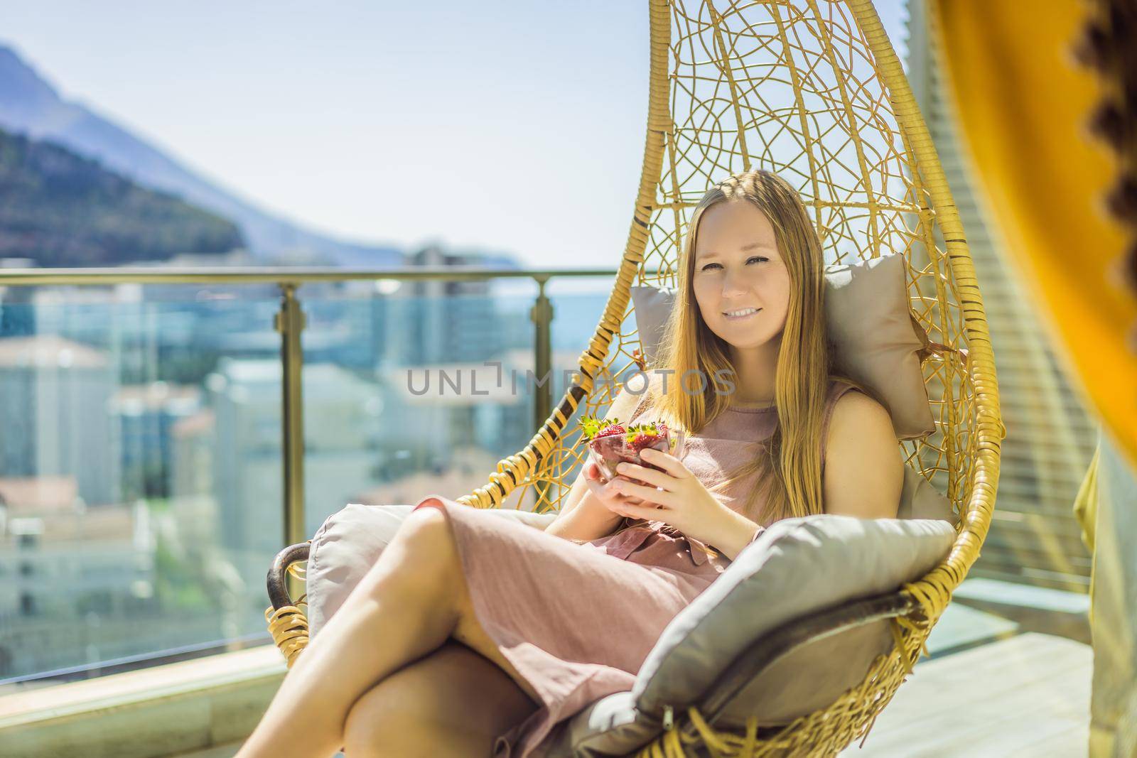 Portrait of gorgeous woman wearing beautiful dress sitting in a patio and eating strawberry.