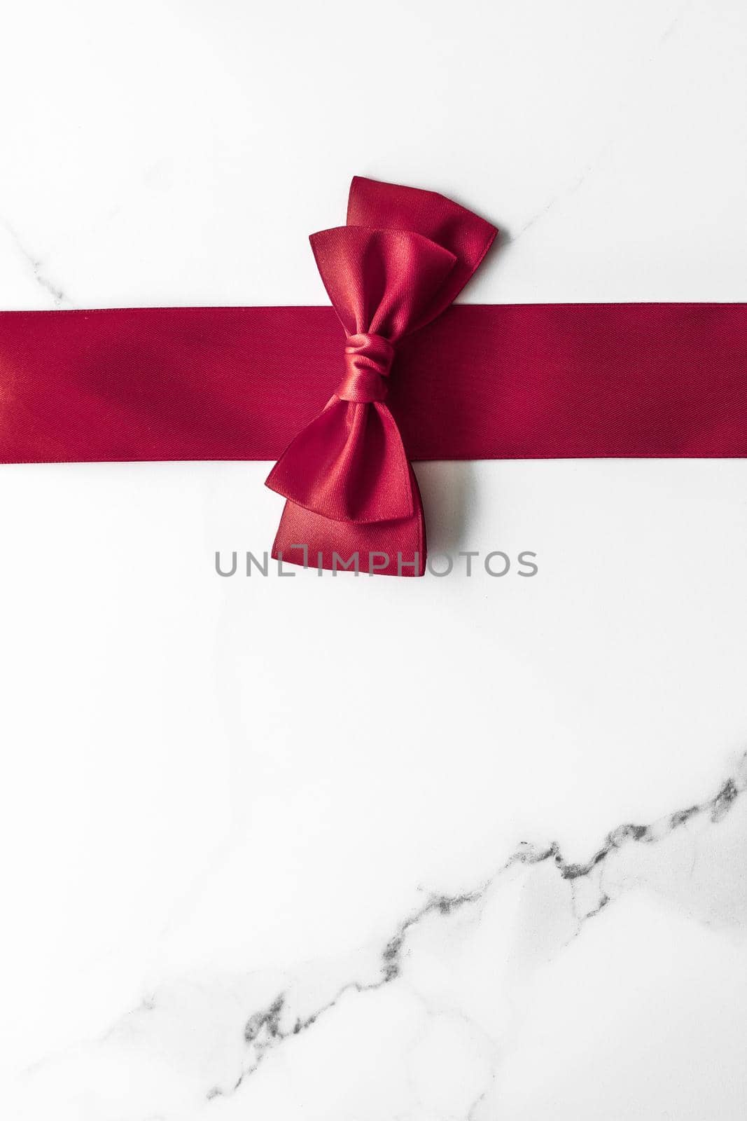 Holiday gift, decoration and sale promotion concept - Bordeaux silk ribbon on marble background, flatlay