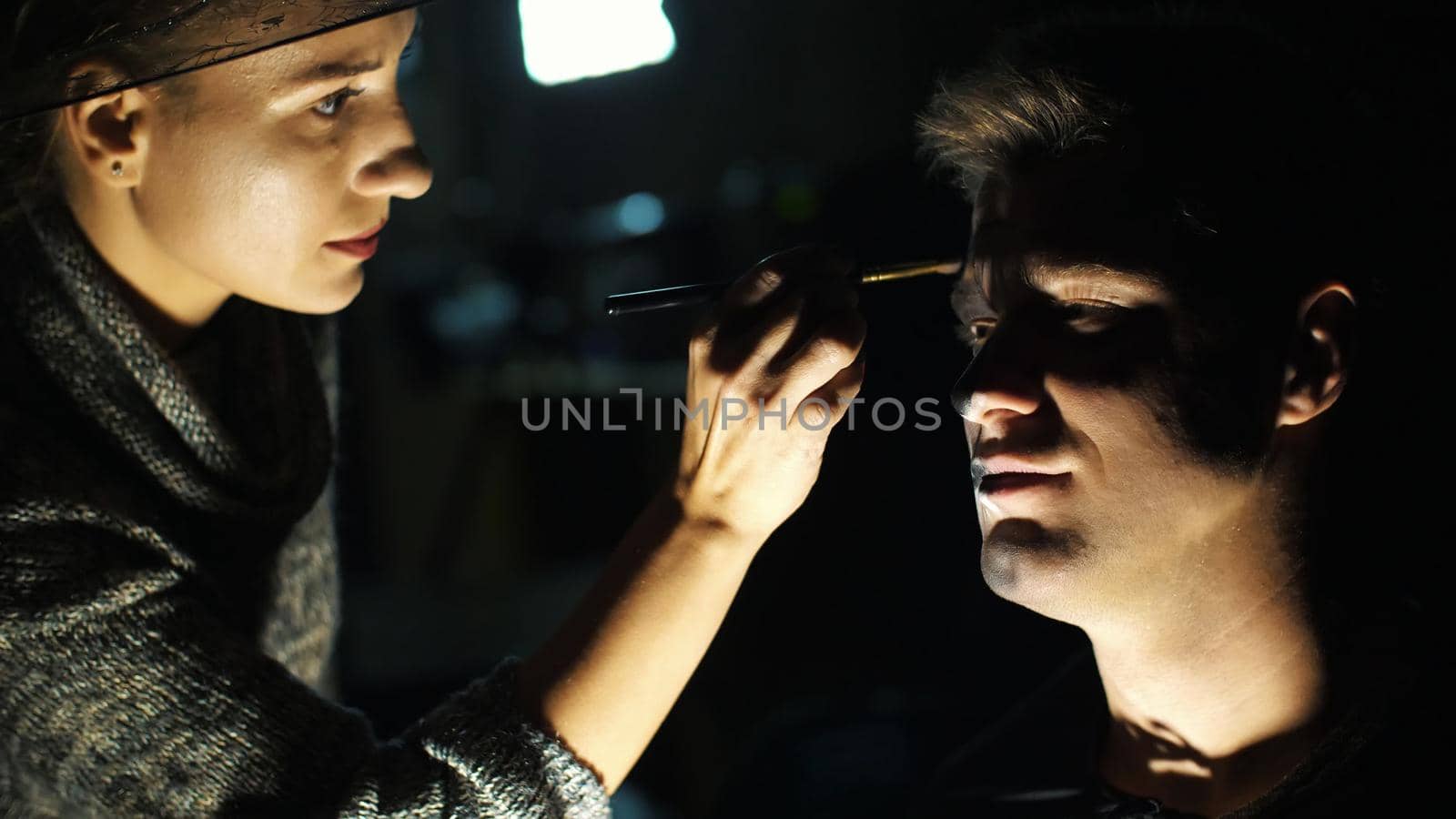 Halloween party, close-up, make-up artist draws a terrible makeup on the face of a man for a Halloween party. High quality photo